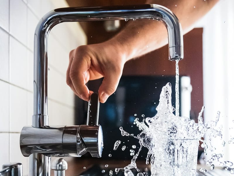 Newly fitted chrome kitchen mixer tap running clear water after a leak repair